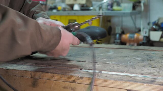 Workshop. The worker uses a special key to replace the drill bit in the drill head with a smaller diameter.