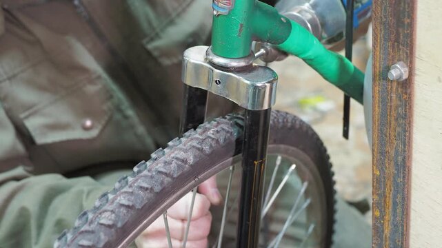 Workshop. A worker uses a drill to make a hole in the steering fork of an old bicycle.