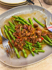 A beautifully arranged plate of delicious food featuring vibrant green beans and succulent pieces of meat placed on a table alongside a fork