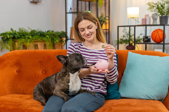 Middle-aged woman with French bulldog at home drops coins into piggy bank calm voice and simple tips. Girl with dog on sofa explains savings plan smiles friendly joke clear budget goal smart habit joy - Powered by Adobe