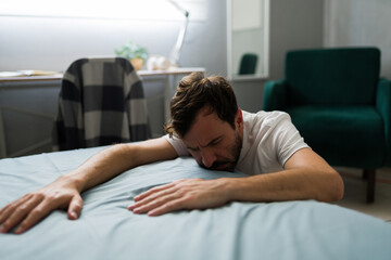 Hopeless man laying face down on bed after breakup