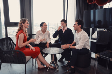 Group of business professionals having casual conversation and networking in modern office lounge with city view..