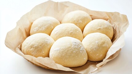 Fototapeta premium A basket filled with eight dough balls wrapped in brown paper. The dough balls are round and dusted with flour, and they are arranged in a circular pattern within the paper basket.
