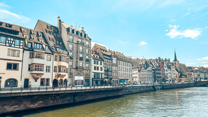 Naklejka premium Scenic riverside view of historic buildings reflecting on water with clear blue sky