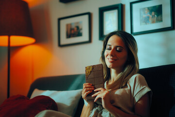 Happy Woman Holding a Pistachio Filled Chocolate. Cheerful lady enjoys overindulging on dessert 