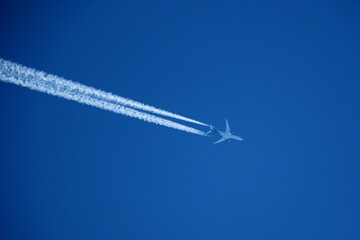 Airplane in the blue sky with contrail. Flight Path Over Blue Sky, travel concept.