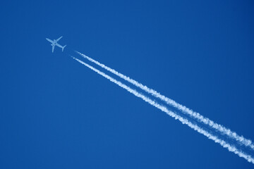 Airplane in the blue sky with contrail. Flight Path Over Blue Sky, travel concept.