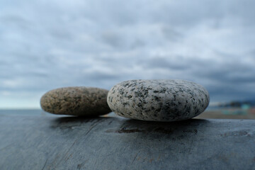 Two stones on the beach. Pebbles on a steel surface with a cloudy sky in the background