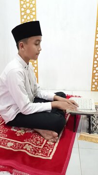 A boy is reading Koran after praying