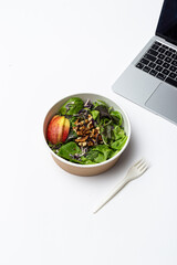 Office lunch concept with fresh green salad and laptop
