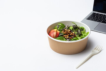 Office lunch concept with fresh green salad and laptop