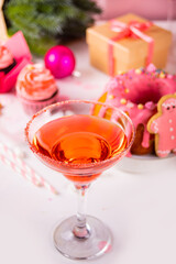 Pink Christmas cocktail. traditional fruit cake and cupcakes on the background. Winter festive table. Holiday celebrate concept.