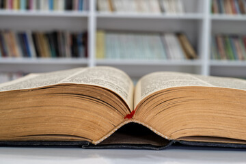 Open Vintage Book Resting on a Table Before Library Shelves, Quiet Study Scene