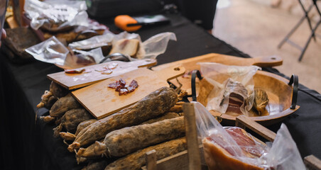Display of assorted cured sausages on a wooden board and trays at a local market. Traditional...