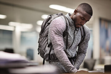 Man adjusting backpack straps, last glance back at office desk.