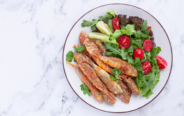 Fried crispy mullet fish, with fresh salad, on a plate with lime, no people,