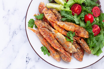 Fried crispy mullet fish, with fresh salad, on a plate with lime, no people,