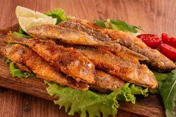 Fried crispy red mullet fish, on a wooden chopping board, with lime, no people,