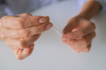 Hands using an at-home rapid antigen test for remote care: self-swab, easy sample, quick result. Ideal for telemedicine, COVID or strep screening, digital health, online doctor pharmacy