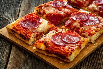Pizza pepperoni with salami, tomato sauce and mozzarella cheese on wooden table	