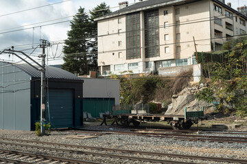 Empty train wagon on railway tracks near buildings and maintenance area.