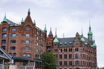 Historic Speicherstadt warehouses and ornate red brick building with green copper spires and clock tower in Hamburg Germany