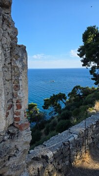 Stone castle ruins in Parga Greece overlooking Ionian Sea. Historic landmark with ancient walls, pine trees and stunning blue water view. Perfect Greek travel and history photo.	