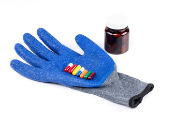 Blue protective glove holding colorful capsules with medicine bottle isolated on white background with clipping path.