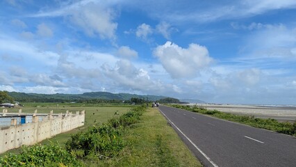 Scenic coastal road a picturesque asphalt road stretches along the coastline, offering breathtaking views of the sea, sky, and lush greenery in bangladesh