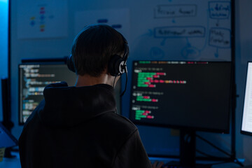 Programmer developer coding software on computer screen monitor night technology workspace. Hacker engineer typing code terminal dark office workstation cyber security internet