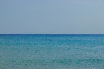 Obraz premium Golden sandy beach with small turquoise waves and blue sea horizon 