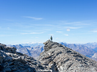 Solo Hiker Standing on Rocky Ridge in the French Alps – Adventure and Freedom in High Mountains