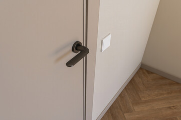 A close-up shows a door with a matte gray finish and a dark handle. A white light switch is visible...