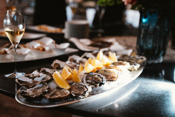 Freshly shucked oysters served on ice with lemon wedges, elegantly presented alongside a glass of champagne, creating a luxurious dining atmosphere suitable for celebrations.