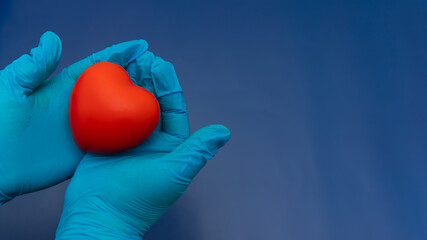 Blue Gloved Hands Holding red Heart On dark Blue Background, Place For Logo, Place For Text, Charity