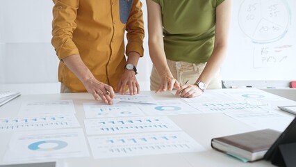 Professional team analyzing financial charts, collaborating intently around conference table in sleek, contemporary workspace. Business people concept