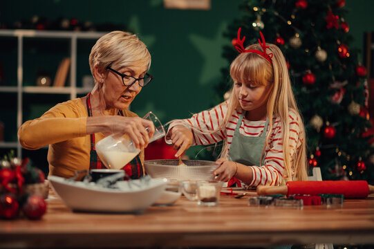Grandmother and granddaughter baking christmas cookies together - Powered by Adobe