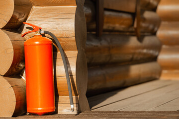  a red fire extinguisher on the porch of a wooden house. Fire safety in a wooden house. place for inscriptions