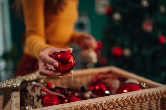 Woman decorating christmas tree taking red bauble from wicker basket
