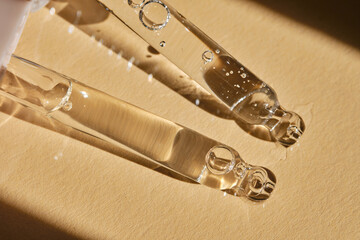 Two pipettes with serum on a beige background.