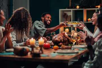 Friends sharing food, celebrating thanksgiving dinner at home