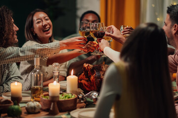 Friends toasting with wine at thanksgiving dinner table