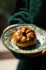 Girl in fluffy green sweater holding vintage plate with homemade pumpkin shaped bun.