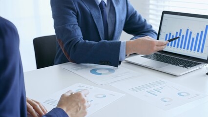 Businesspeople reviewing financial data, analyzing charts and graphs, pointing at laptop screen during collaborative meeting. Business people and finance concept