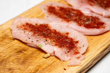 Raw Chicken Breast Seasoned with Paprika and Pepper on Kitchen Table