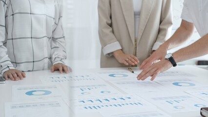 Business team analyzing financial charts and graphs, pointing at statistics and discussing data, working together on business project in modern office. Business people concept