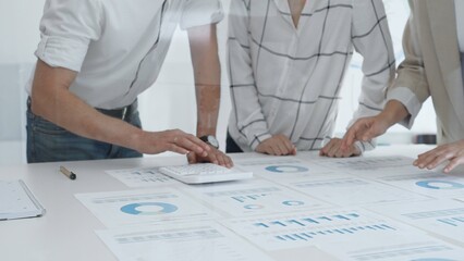 Professional team reviewing financial charts and graphs, working together in modern office space, developing strategic improvements. Business people concept