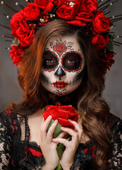 real person close-up portrait body art woman sugar skull make-up beauty face eyes lips, hand holding red rose flower. Black Halloween holiday make up. Sexy Girl Calavera day of the dead santa muerte