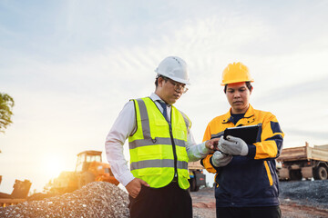 Construction Workers Collaborating on Project with Tablet at Construction Site During Sunset in Modern Urban Environment