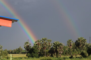 Rainbow Spectacle: A vibrant double rainbow arcs gracefully across the sky above a scenic...